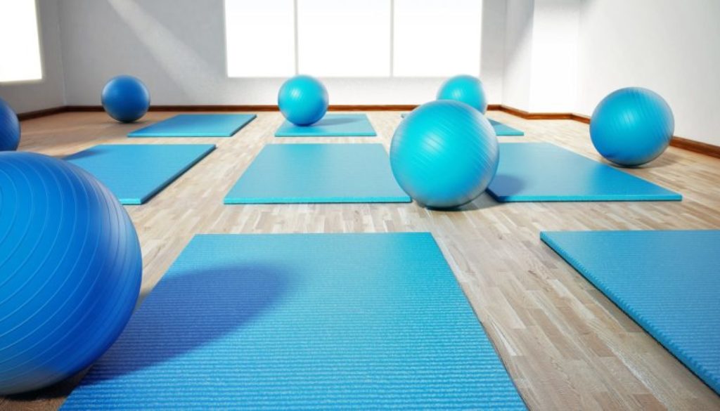 Pilates mat and exercise balls standing on parquet floor. 3D illustration