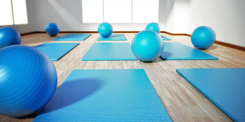 Pilates mat and exercise balls standing on parquet floor. 3D illustration